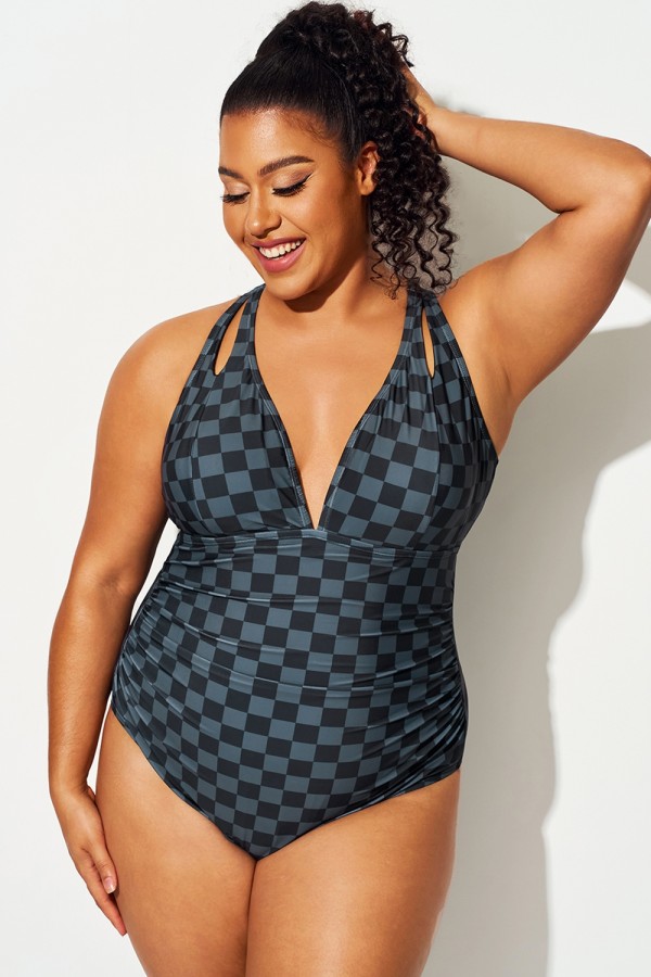 Traje de baño de una pieza negro con abertura en el hombro y estampado a cuadros.